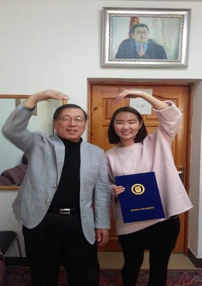 Dean JangGyo Ahn and Zolzaya Ulziibayar form a heart while posing with Zolzaya’s diploma.